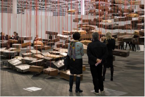 Três pessoas em pé observando uma exposição de caixas flutuantes